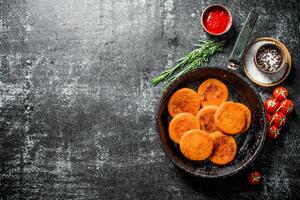 vis schnitzels in pan met specerijen, saus, rozemarijn en tomaten. foto