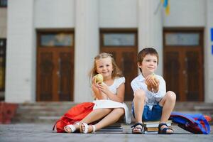 twee leerlingen van primair school. jongen en meisje met school- Tassen achter de rug. begin van school- lessen. warm dag van val. terug naar school. weinig eerste klassers. foto