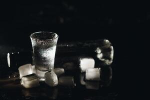 wodka in schot bril Aan zwart achtergrond, bevroren sterk drinken in beneveld glas. foto