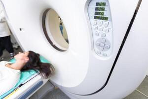 mooi, jong vrouw gaan door een geautomatiseerd axiaal tomografie kat scannen medisch test examen in een modern ziekenhuis foto