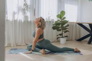 een 50 jaar oud vrouw doet yoga Bij huis foto