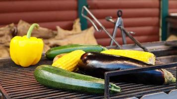 groenten grillen tijdens een buitenbarbecue of op een picknick. man voorbereiding van een plantaardige barbecue, in de zomer, direct zonlicht achtergrond. zomergevoel. gerookt veganistisch voorgerecht. foto