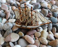 miniatuur van zeil schip over- klein zee stenen. strandde schip concept voorraad foto met zacht focus