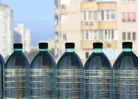 plastic flessen met schoon water Aan de venster in een hoog stijgen appartement foto