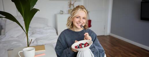 portret van jong vlogger, inhoud Schepper, tonen haar eigengemaakt ontbijt Aan camera, aan het eten nagerecht, glimlachen en op zoek gelukkig foto