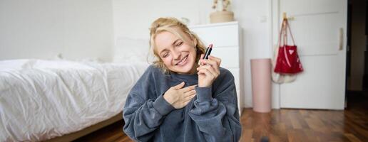 portret van jong inhoud Schepper, vrouw met sociaal media account, opname over bedenken Aan digitaal camera, Holding favoriete lippenstift, aanbevelen Product naar publiek online foto