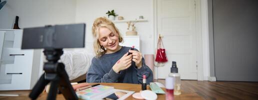 portret van mooi jong vrouw, inhoud Schepper voor sociaal media, zittend in voorkant van digitaal camera, opname over verzinnen, tonen lippenstift stalen Aan haar huid foto