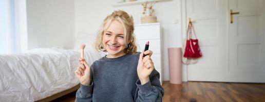 beeld van jong vrouw inhoud Schepper, schoonheid blogger zit Aan verdieping in haar kamer, records over verzinnen, shows lippenstift Aan camera foto