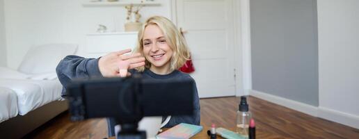 dichtbij omhoog portret van gelukkig jong schoonheid blogger, records levensstijl vlog in haar kamer, gebruik makend van camera met stabilisator, shows bedenken borstel en schoonheidsmiddelen foto