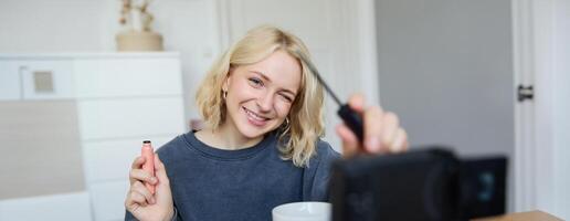 glimlachen jong mooi levensstijl blogger, meisje records een schoonheid vlog in haar kamer, gebruik makend van professioneel camera, tonen bedenken schoonheidsmiddelen naar haar volgers, creëert inhoud voor sociaal media foto