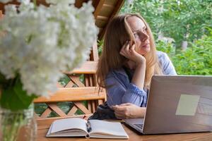 jong gelukkig vrouw focust Aan haar laptop in houten prieel. ontspannen buitenshuis instelling benadrukt comfort en productiviteit. afgelegen werk aan het leren concept foto