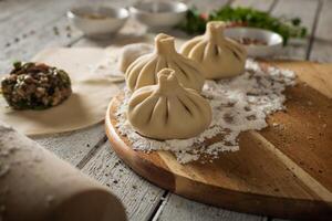 dichtbij omhoog naar Kaukasisch khinkali knoedels schotel geserveerd Aan bord. achtergrond met ingrediënten en verspreide specerijen foto