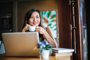 mooie vrouw die werkt met een laptopcomputer in het café van de coffeeshop foto