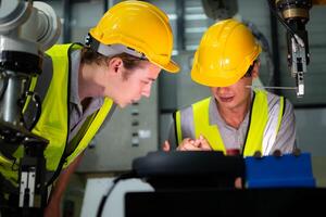 een technicus lijdt een hand- ongeluk terwijl werken met een robot arm in een fabriek met collega's het verstrekken van bijstand foto