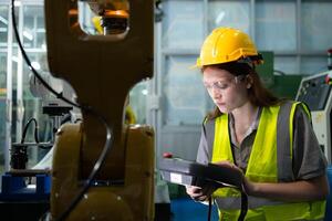 vrouw technicus wie handhaaft een klein robot arm de operatie van een klein robot arm gebruikt in industrie is wezen gerepareerd. foto