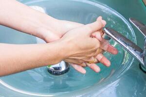 meisje het wassen haar hand- en beurt uit kraan foto