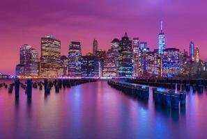 skyline van manhattan 's nachts met veelkleurige reflecties in het water, uitzicht vanaf brooklyn, new york, vs foto