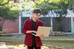 portret van Aziatisch college leerling gebruik makend van laptop op zoek naar camera. een Mens werken met een laptop computer Bij campus foto