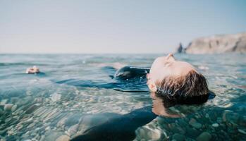 vrouw zwemmen in zee Bij zonsondergang, vlotter Aan kalmte water terug visie. concept van lichaam beeld en fitheid, genieten van een sereen strand. gelukkig vrouw met perfect fit lichaam geniet zee strand foto