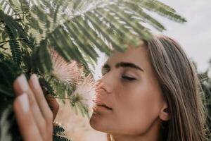 schoonheid portret van gelukkig vrouw detailopname. jong meisje ruiken Chinese acacia roze bloeiende bloemen. portret van jong vrouw in bloeiend lente, zomer tuin. romantisch uitstraling. vrouw en natuur foto