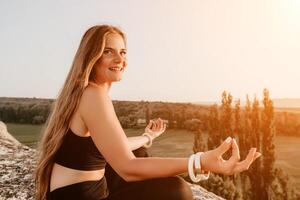 geschiktheid vrouw. gelukkig middelbare leeftijd geschiktheid vrouw aan het doen uitrekken en pilates Aan een rots in de buurt Woud Bij zonsondergang. vrouw geschiktheid yoga routine. gezond levensstijl met focus Aan welzijn en ontspanning. foto