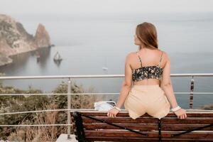 vrouw reizen zee. gelukkig toerist genieten nemen afbeelding buitenshuis voor herinneringen. vrouw reiziger looks Bij de rand van de klif Aan de zee baai van bergen, sharing reizen avontuur reis foto