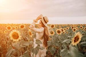 vrouw in zonnebloem veld. gelukkig meisje in een rietje hoed poseren in een enorm veld- van zonnebloemen Bij zonsondergang, genieten nemen afbeelding buitenshuis voor herinneringen. zomer tijd. foto