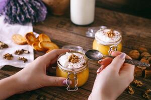 vrouwen handen met lepel. eigengemaakt pompoen taart milkshake in glas pot met geslagen room foto