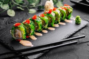 groen draak sushi rollen Aan zwart leisteen foto