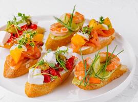 elegant schotel van geassorteerd bruschetta met vers toppings Aan een wit achtergrond foto