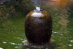 keramisch fontein pot geïnstalleerd Bij de vijver in de tuin van de huis. het is pottenbakkerij voor decoreren huizen en tuinen naar worden mooi, schaduwrijk, natuurlijk en verbeteren feng shui. foto