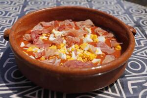 Spaans voedsel, verkoudheid tomaat soep gebeld salmorejo met gekookt ei en rauw ham foto