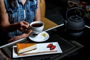 vrouw Bij tafel genieten van plak van taart en kop van thee foto