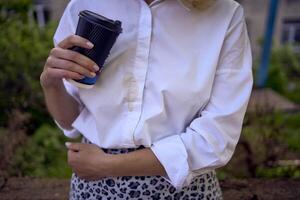 midden- leeftijd vrouw in jaren 70, 80s stijl kleren gemorst koffie Aan haarzelf gedurende een breken buiten foto