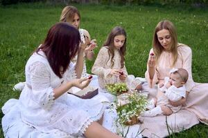 twee Dames en hun kinderen hebben een picknick Aan de gazon foto