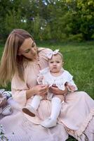 twee Dames en hun kinderen hebben een picknick Aan de gazon foto