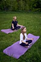 een vrouw en meisje Doen yoga en mediteren in natuur foto