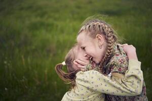 twee zussen knuffel en kus in de veld- foto