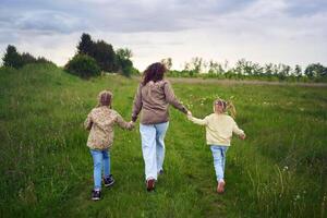 moeder en kinderen rennen Holding handen in de veld- foto