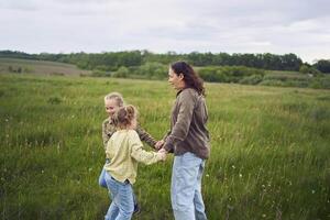 een moeder en twee zussen cirkel in de veld- Holding handen foto