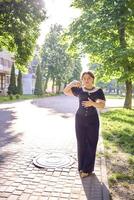 een medium grootte vrouw in een zwart korset en breed been broek wandelingen door de stad in de ochtend- licht foto