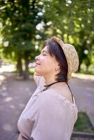 plus grootte vrouw in perzik dons jurk met hoed hebben pret Aan ochtend- stad straten foto