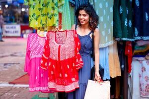 dame wandelen in blauw jurk Holding boodschappen doen Tassen terwijl wandelen in sarojini markt Delhi foto