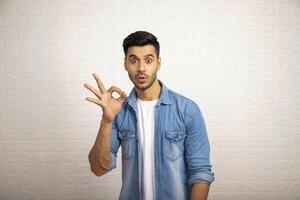Aziatisch Mens met verrast gezicht uitdrukking maken super OK gebaar met hand- foto