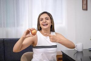 vrouw lachend terwijl richten haar vinger Aan appel foto