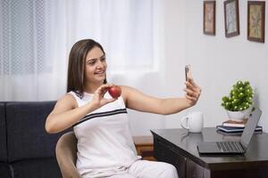 schattig sexy dame tonen rood appel naar vriend Aan telefoontje foto