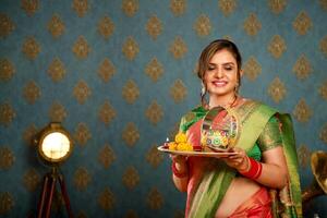 beeld van model- glimlachen in Saree terwijl Holding puja bord gedurende karwa chauth festival foto