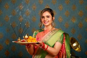 een traditioneel meisje Holding pooja bord gedurende festival van diwali foto