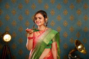 een mooi Aziatisch model- in Saree vieren diwali Holding diya in een hand- foto