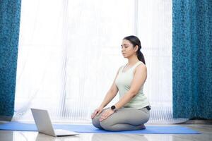 vredig vrouw mediteren in voorkant van laptop Bij huis foto